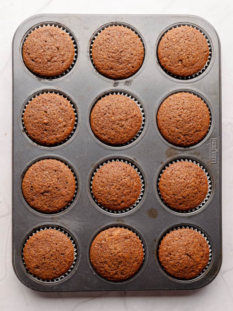 Metal muffin pan with gingerbread cupcakes.