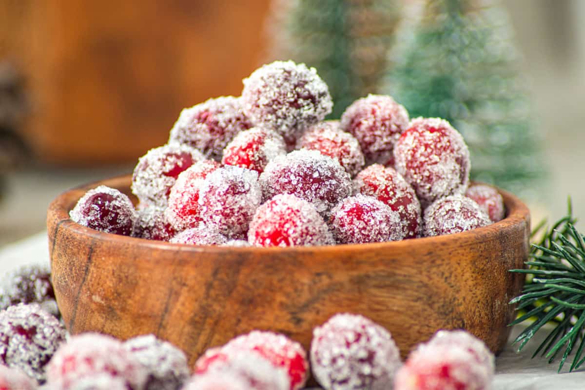 Pile of sugared cranberries in a wooden bowl.