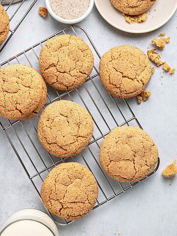 Several crackly snickerdoodles on wire racks. Light gray surface.