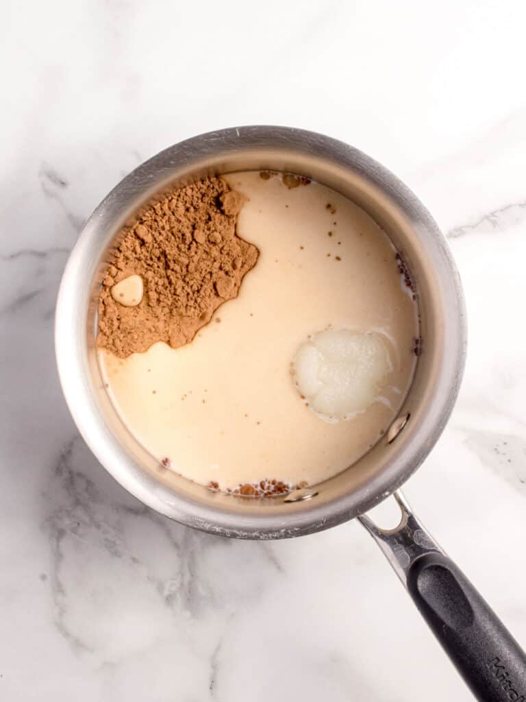 Saucepan with cream and brown sugar. White marbled background.