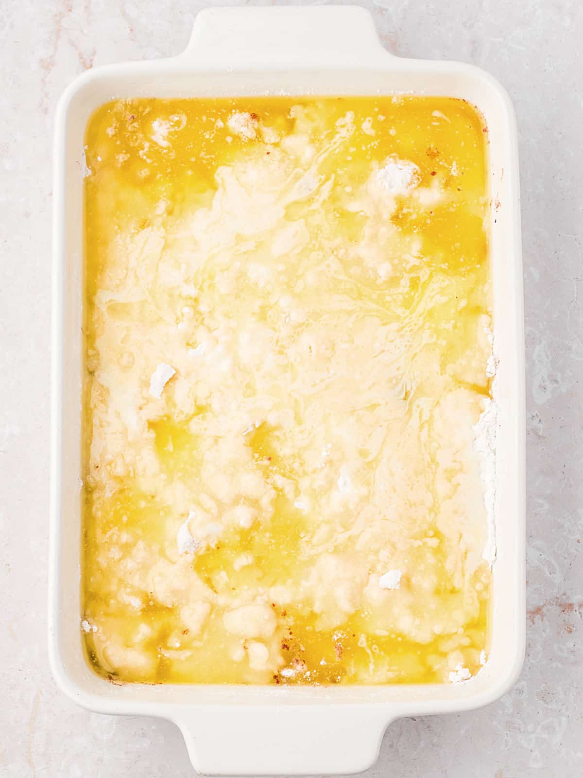 Melted butter topped cake mix in a white baking dish.