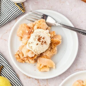 Serving of pear cobbler with ice cream on a white plate. Silver fork.