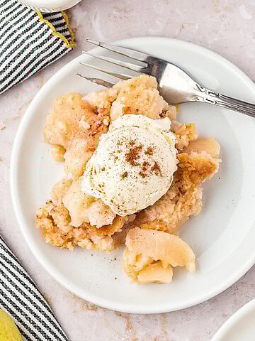 Serving of pear cobbler with ice cream on a white plate. Silver fork.