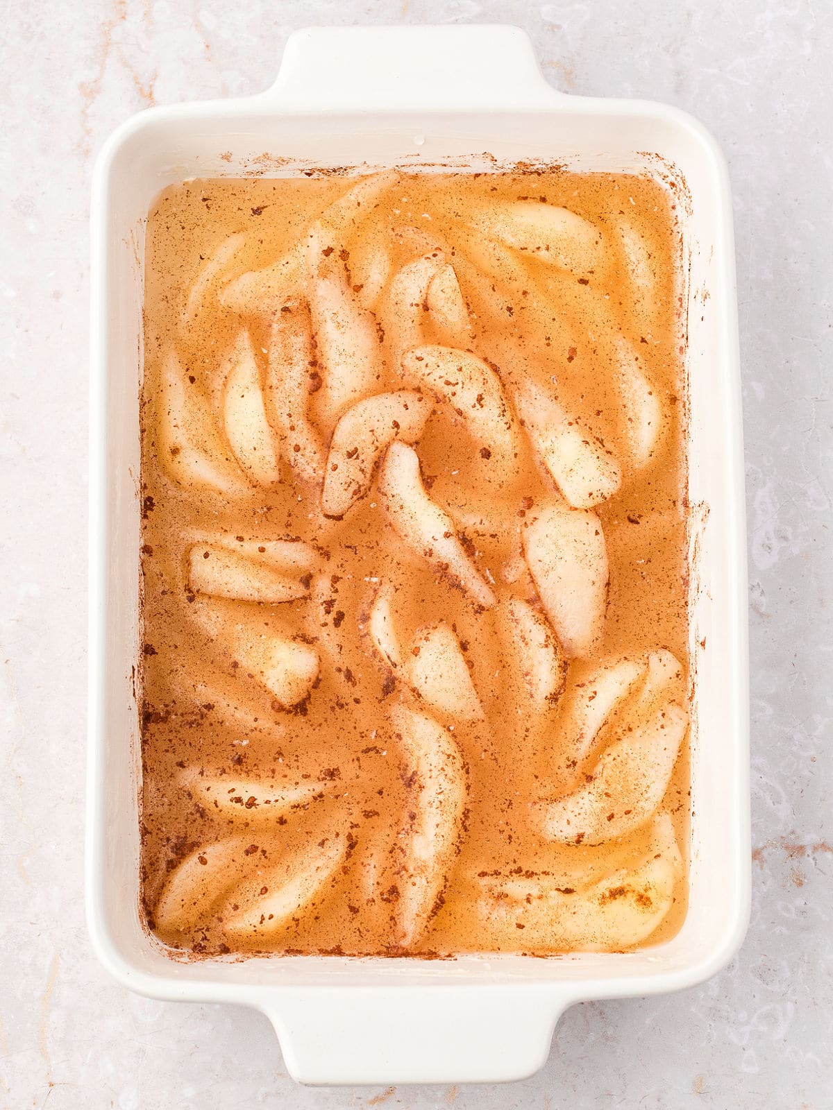 Filling for pear cobbler in a rectangular ceramic white dish.