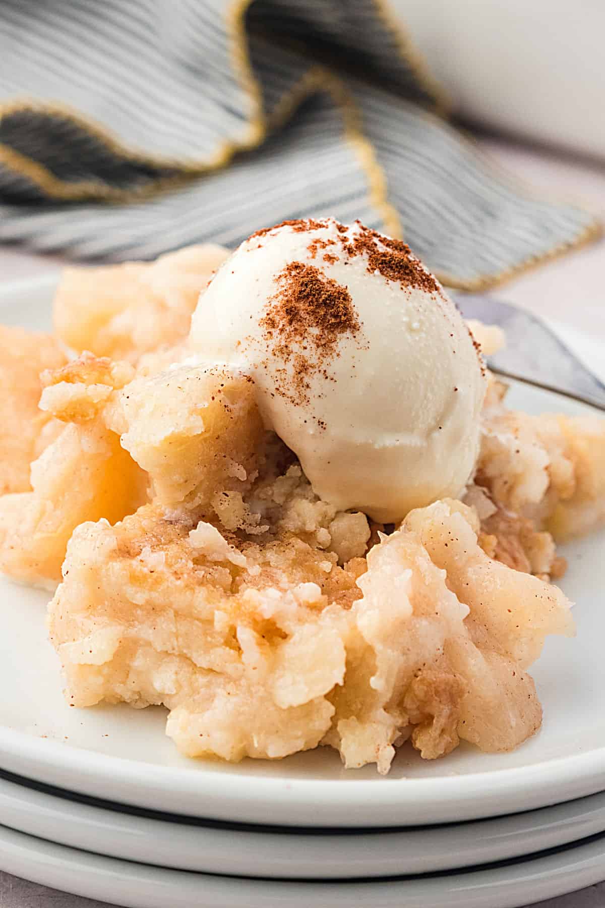 Ice cream topped serving of pear dump cake on white plates.