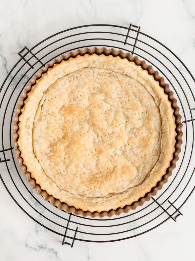Blind baked pie crust in a metal pan on a wire rack. 