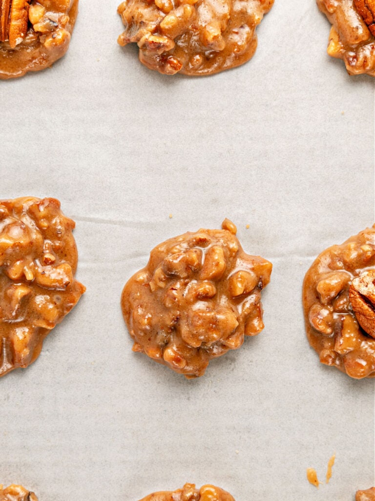 Mounds of pecan pralines mixture on a white parchment paper.