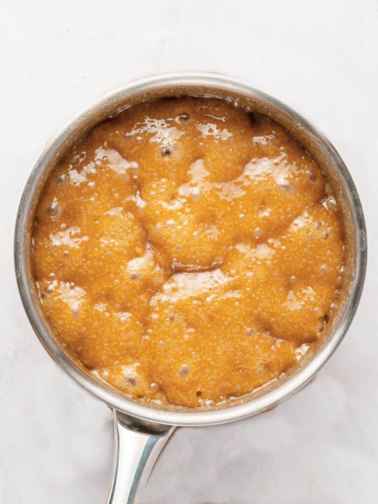 Butterscotch for pralines boiling in a metal saucepan.