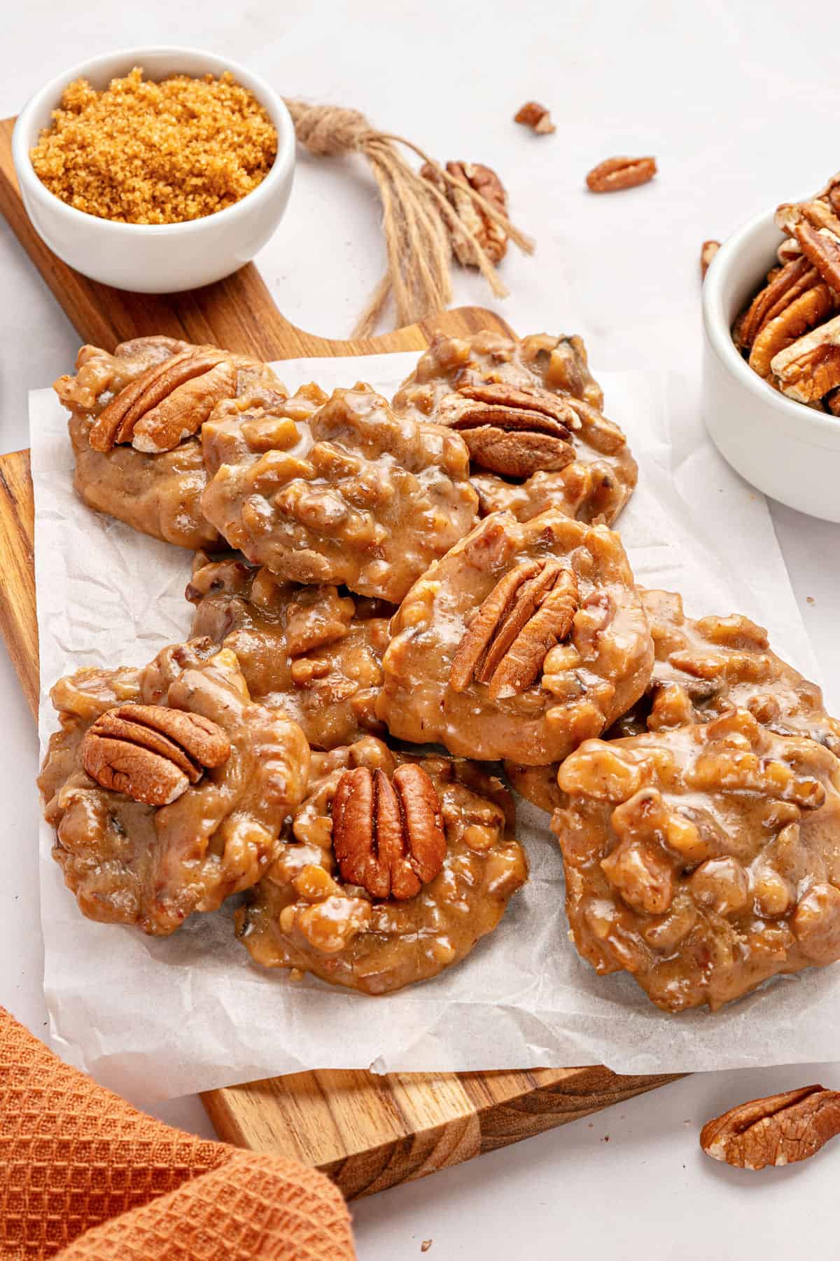 White paper on a wooden board with pecan pralines.