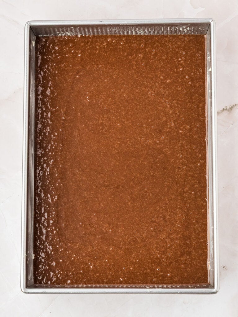 Silver metal rectangular pan with chocolate cake batter.