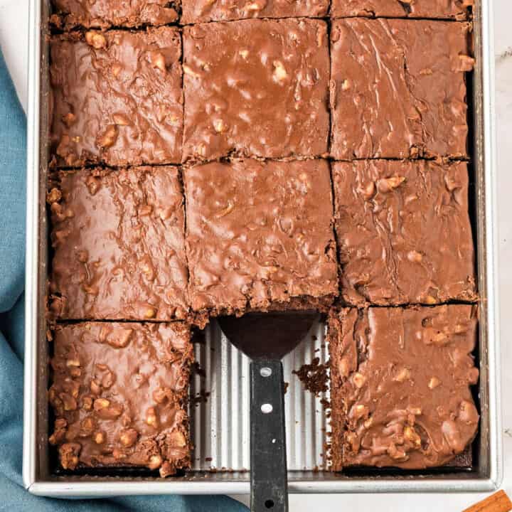 Metal pan with chocolate walnut sheet cake. Spatula, square missing.