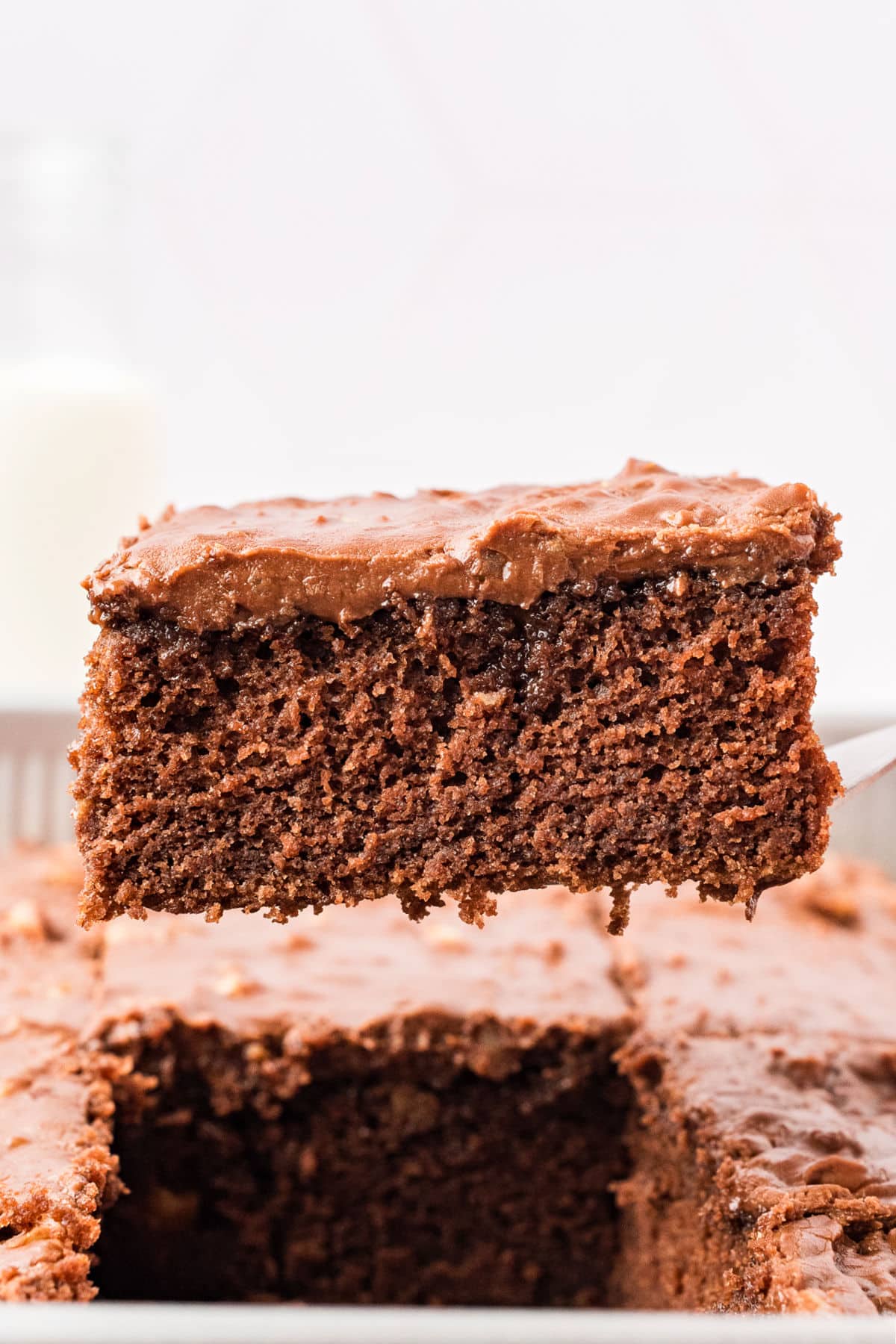 Lifting a square of chocolate frosted cake.