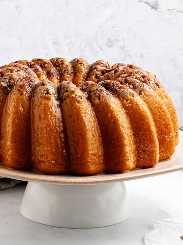 Whole rum bundt cake on a white cake stand. White background.