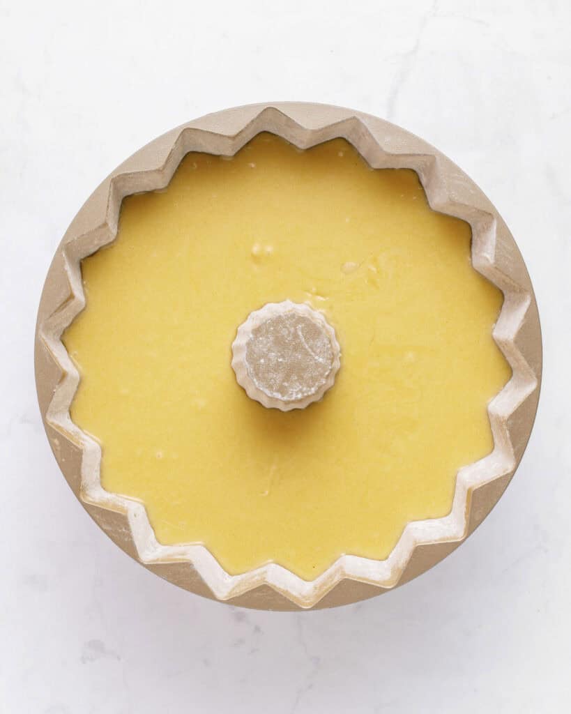 Yellow cake batter in a bundt pan. White background.