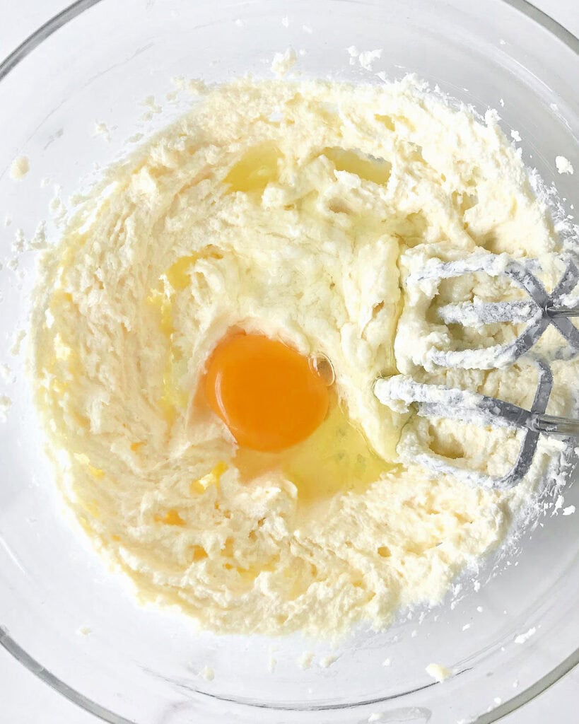 Glass bowl with butter, sugar and egg mixture. Metal beaters.
