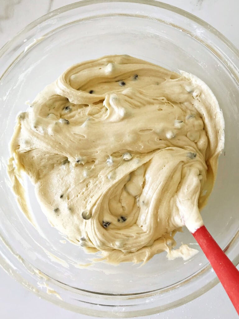 Red spatula in a glass bowl with chocolate chip cake batter.