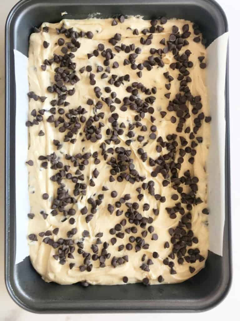 Rectangular dark metal cake pan with chocolate chip cake batter.