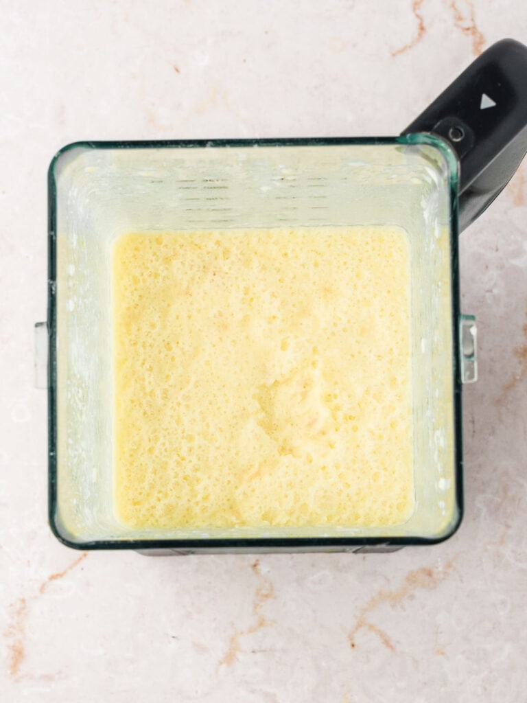Blender jar with mixture for coconut pie filling. Grayish surface.