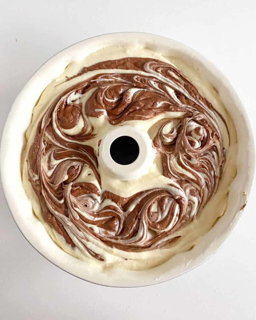 White bundt pan with marbled cake before baking.