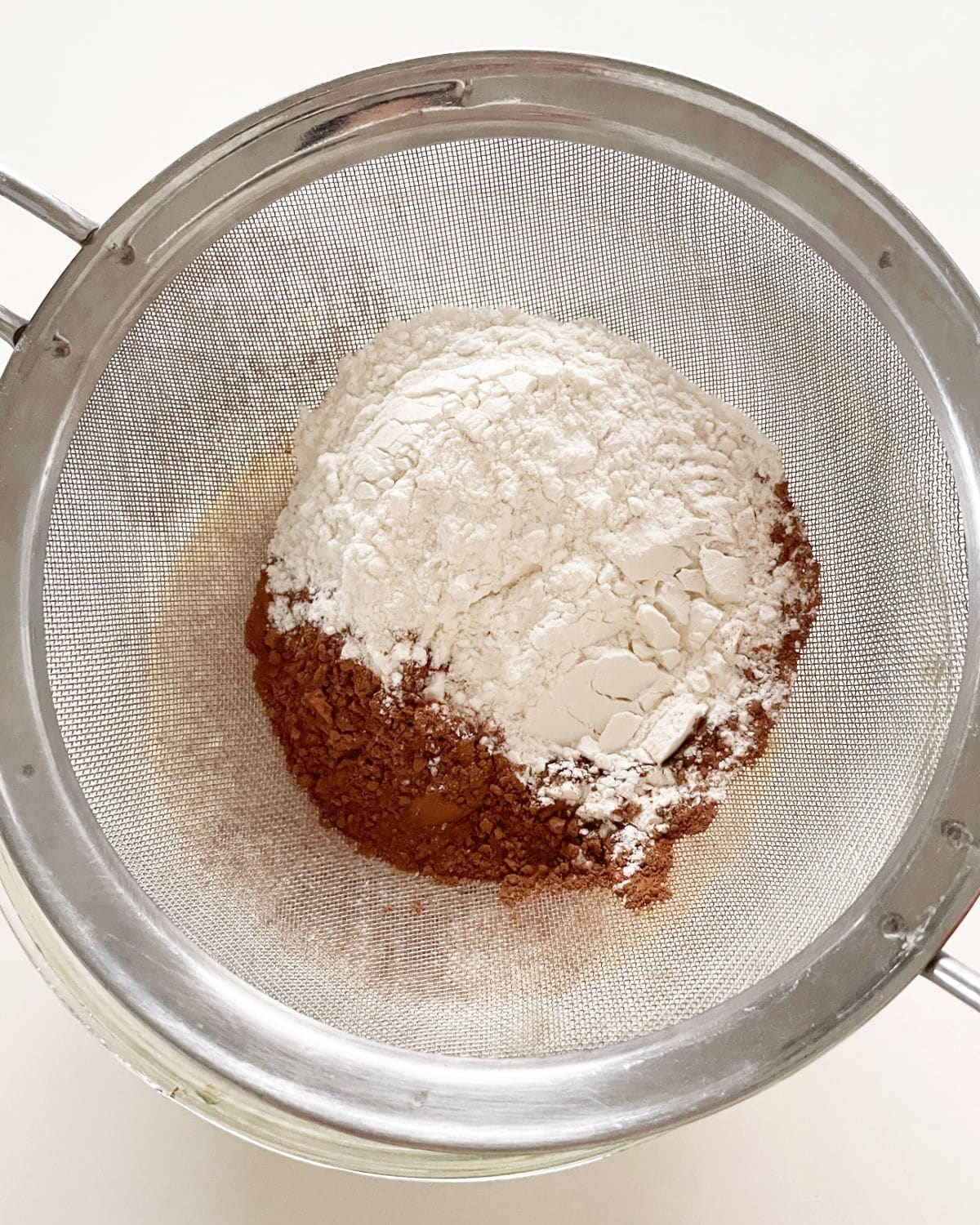 Sifting flour and cocoa with a metal fine mesh sifter.