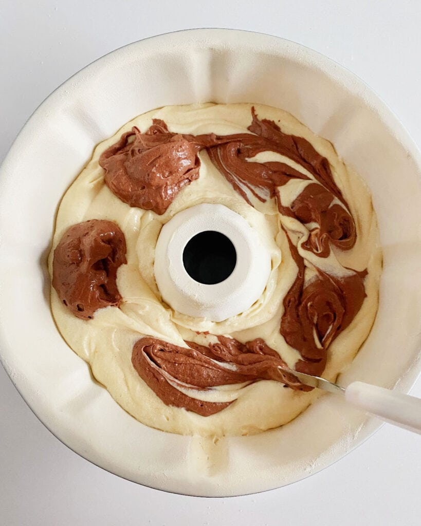 Marbling chocolate batter with the tip of knife; white bundt pan.