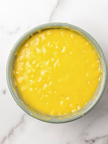 Bowl of passion fruit curd on white marble.