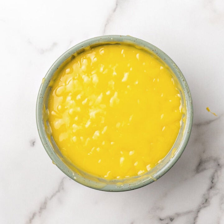 Bowl of passion fruit curd on white marble.