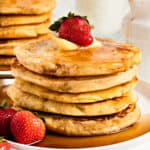 Close up stack of pancakes with syrup and fresh strawberries. White background.
