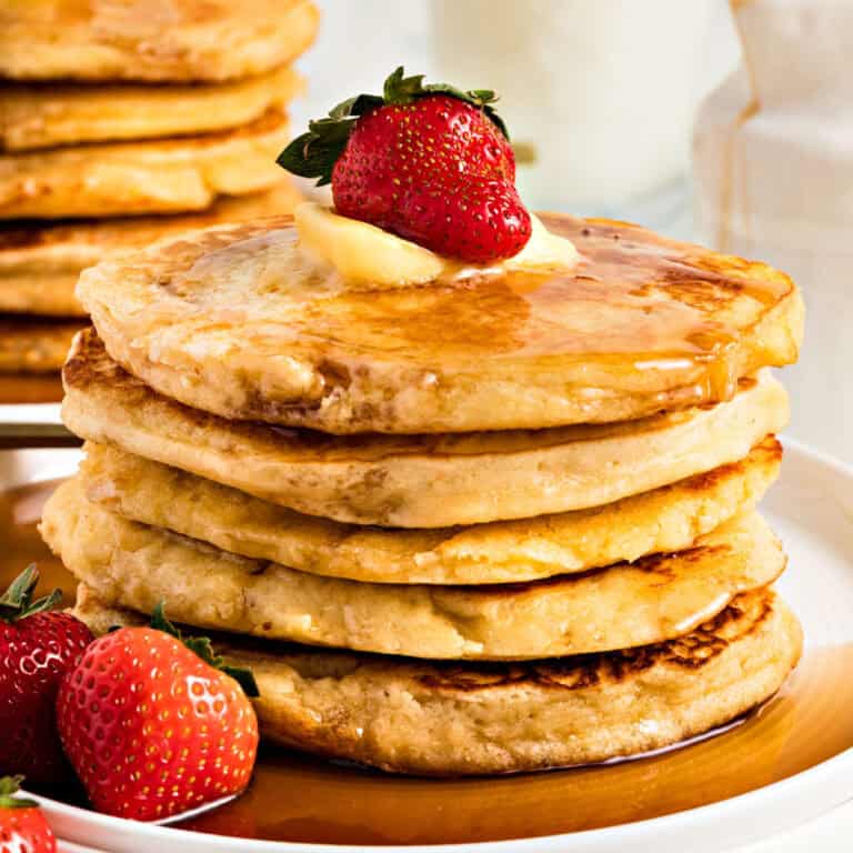 Close up stack of pancakes with syrup and fresh strawberries. White background.