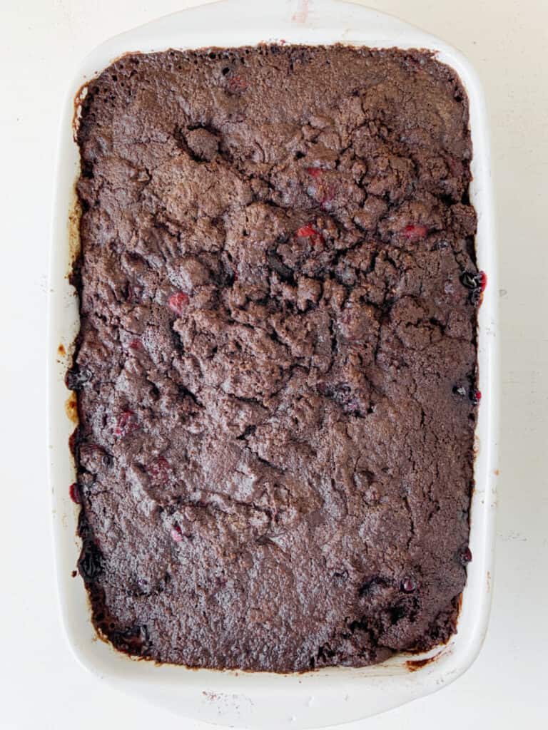 Baked chocolate cherry dump cake in a rectangular dish. White background.