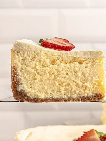Single slice of cheesecake with fresh strawberry slice. Tile background.