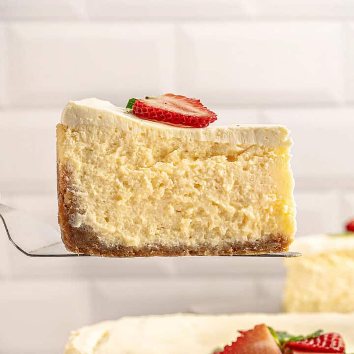 Single slice of cheesecake with fresh strawberry slice. Tile background.