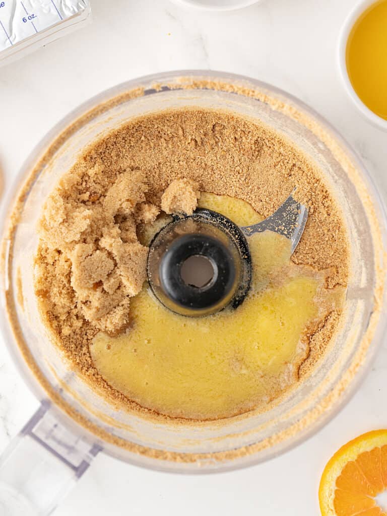 Food processor bowl with graham crumbs and melted butter.