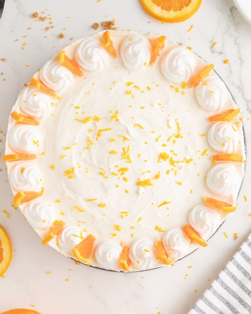 Whole, decorated orange cheesecake. White background. Top view.