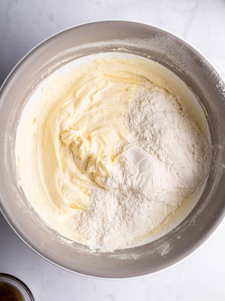 Metal bowl with vanilla cake batter and flour.