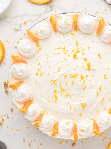 Decorated whole orange cheesecake. White background. Top view.