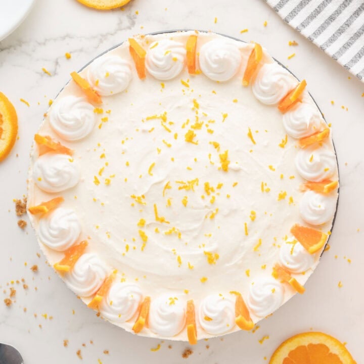 Decorated whole orange cheesecake. White background. Top view.