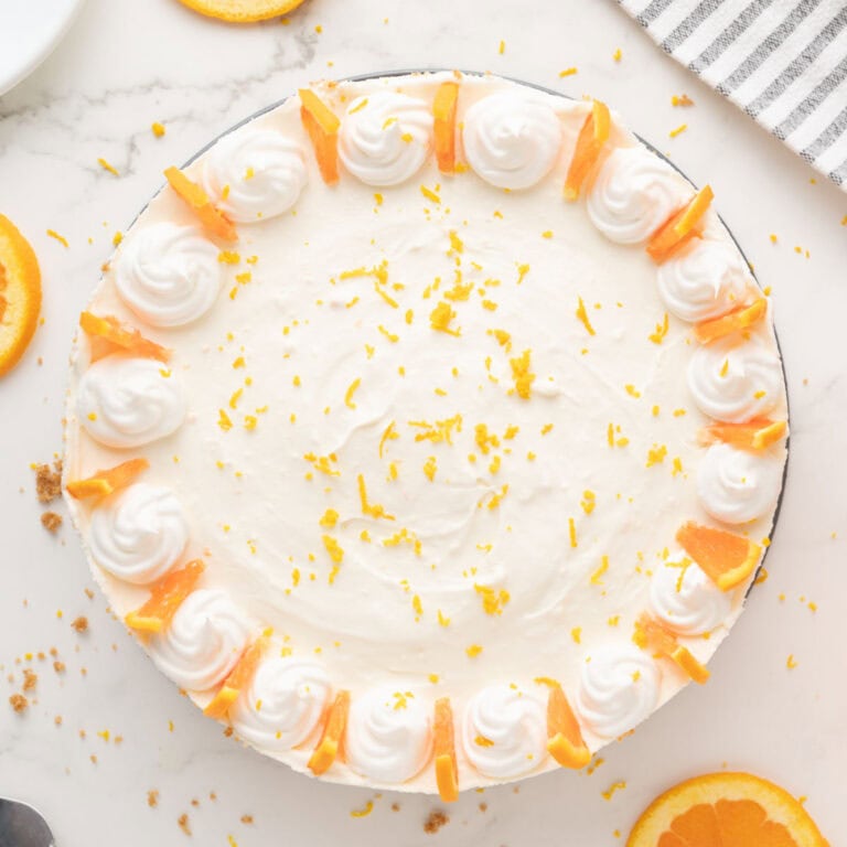 Decorated whole orange cheesecake. White background. Top view.