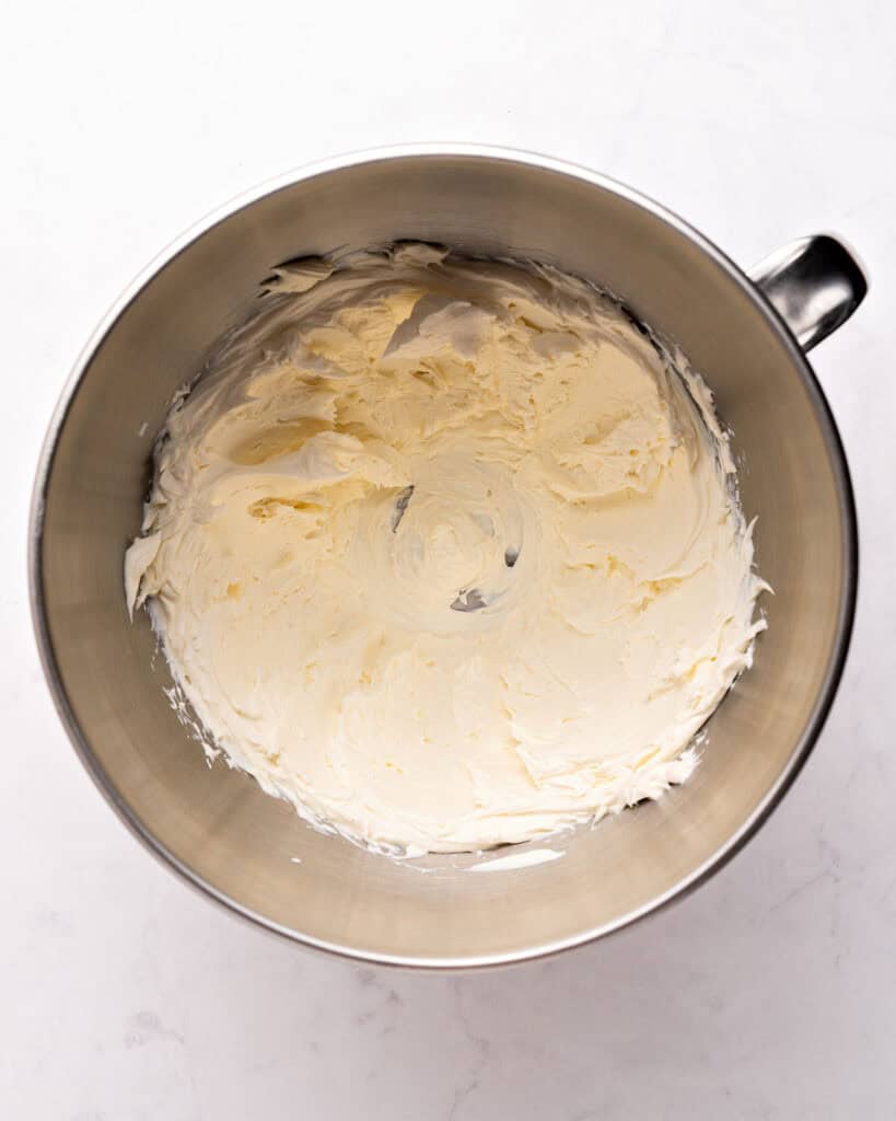 Metal bowl with cheesecake filling. Light gray background.