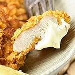 Brown and blue text overlay on forked bite of cornflake chicken with mayo.