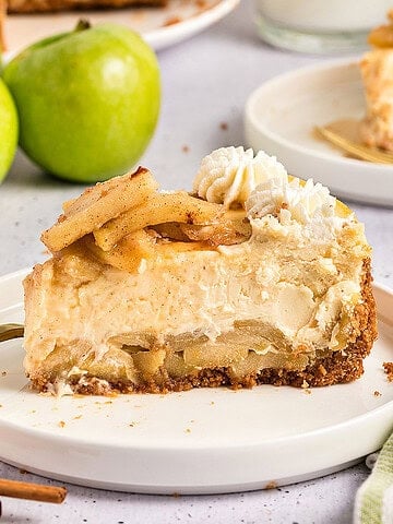 Single slice of apple cheesecake on a white plate. Light gray background, whole green apples.