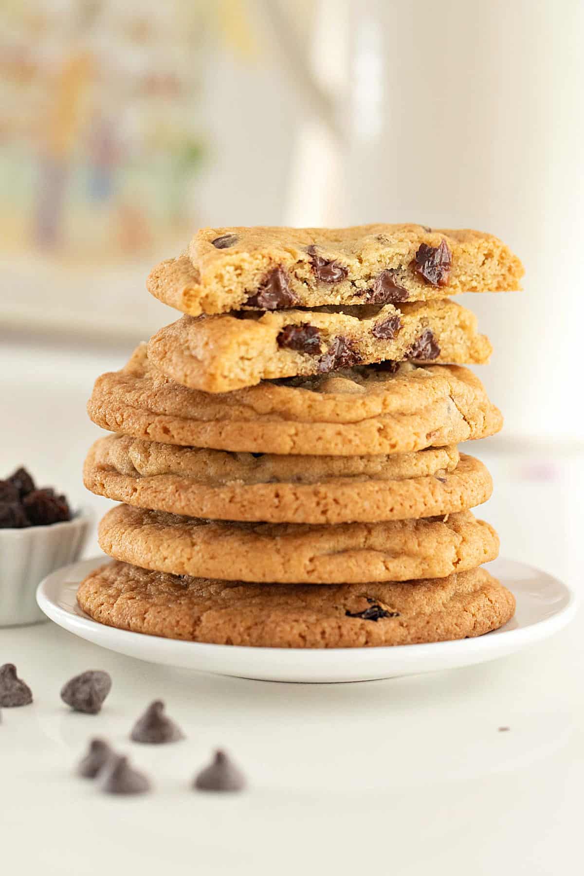Stacked chocolate chip raisin cookies on a white plate. White background. Loose chips.