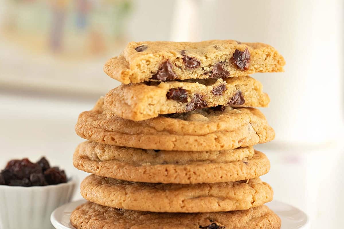 Close up stack of whole and halved raisin chip cookies. Difused whitish background.