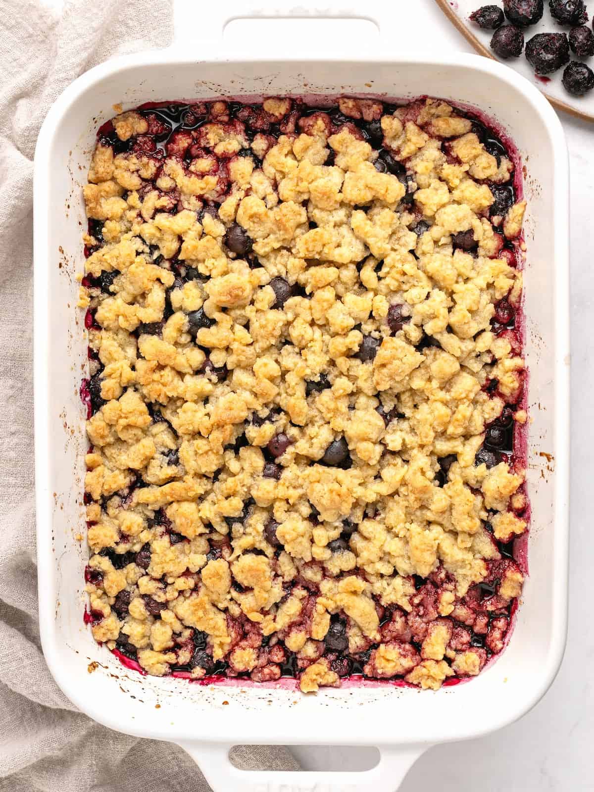 Baked blueberry crumble in a white baking dish. Top view.