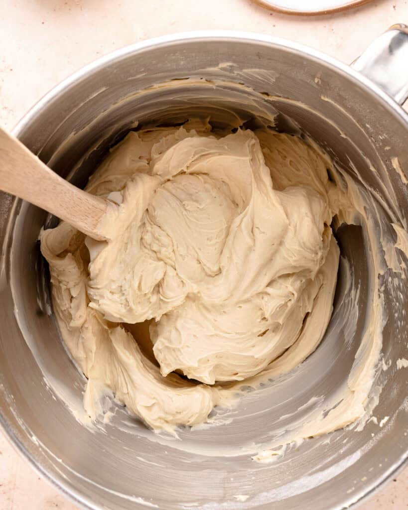 Metal mixer bowl with mascarpone cream for tiramisu cheesecake. Wooden spatula.