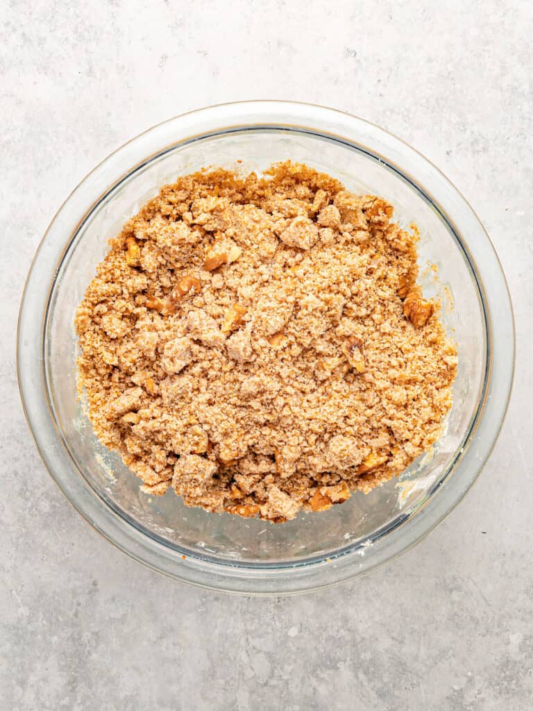 Glass bowl with brown sugar walnut streusel mix. Light gray surface. Top view.
