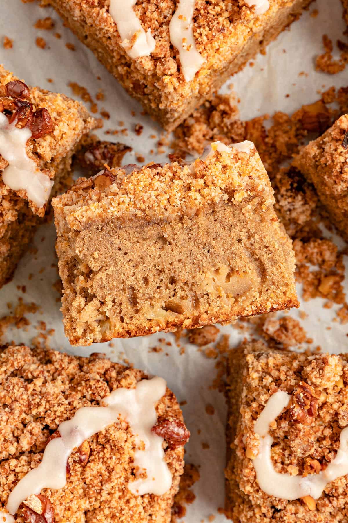 Close up square of applesauce crumb coffee cake with more pieces around.
