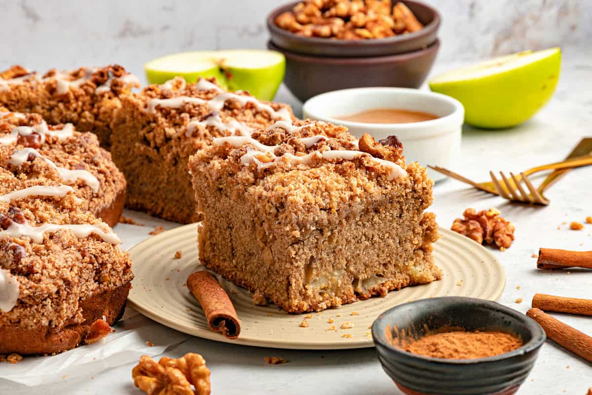 Beige plate with applesauce coffee cake. Mores squares, apple slices, pecans and cinnamon around.