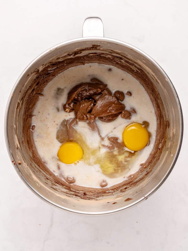 Eggs, buttermilk and cocoa for chocolate cake in a stand mixer bowl. Top view. Whitish surface.