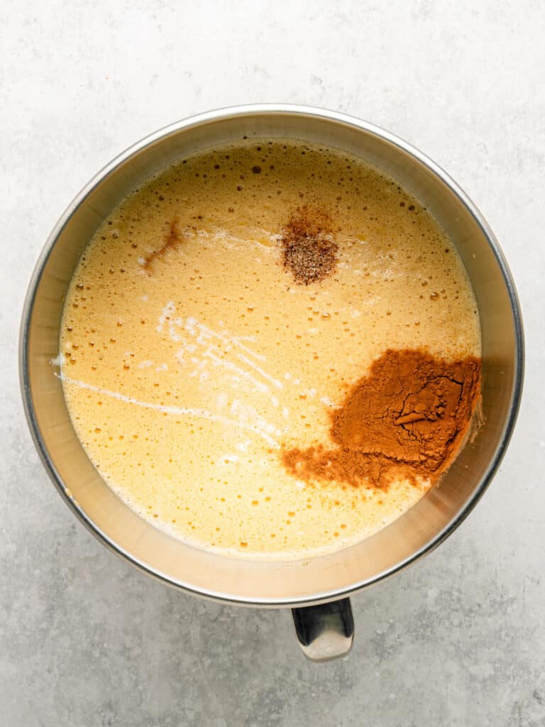 Stand mixer bowl with cinnamon custard mixture. Top view, light gray background.